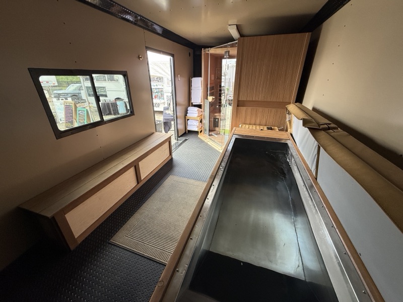 Open cold plunge with bench seating and a view through the trailer door